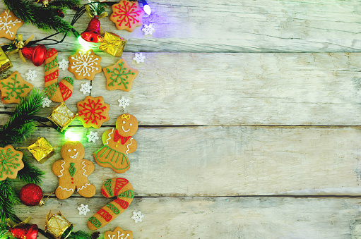 Wood background with gingerbread cookies, Christmas tree and Christmas light. copy space. toning. selective focus