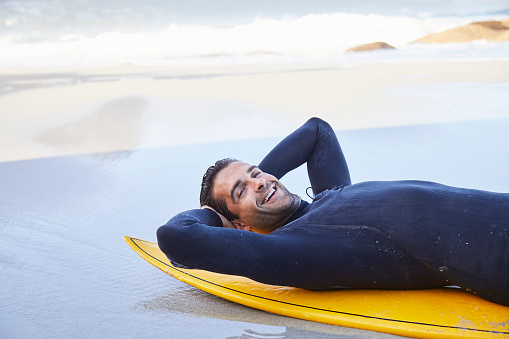 Relaxing surf dude on board on beach, portrait