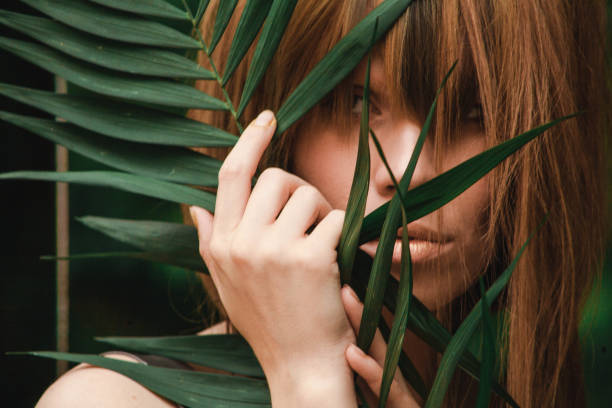 istock Incredibly beautiful girl covers her face with a palm branch 841477894