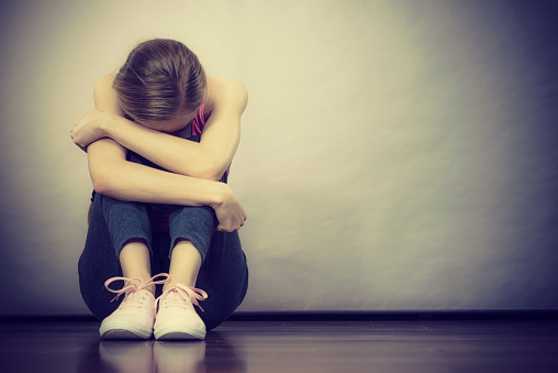 Triste deprimida joven adolescente sentado por pared photo