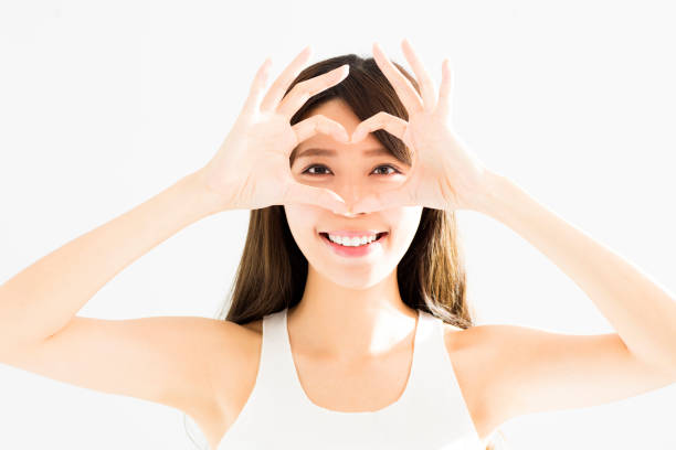 Happy young Woman Holding Heart Shaped Hands Near Eyes - fotografia de stock