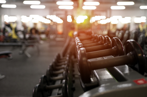 Rows of different dumbbell weights in modern fitness center. Gym equipment background. Shallow depth of field.