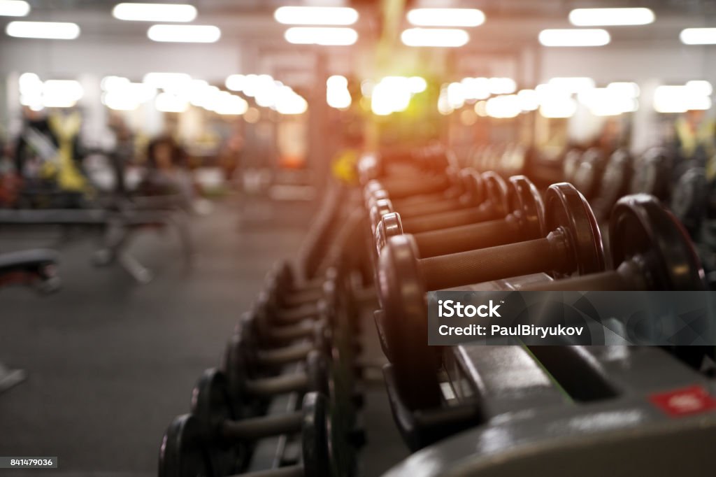 Different dumbbell weights in fitness center Rows of different dumbbell weights in modern fitness center. Gym equipment background. Shallow depth of field. Gym Stock Photo