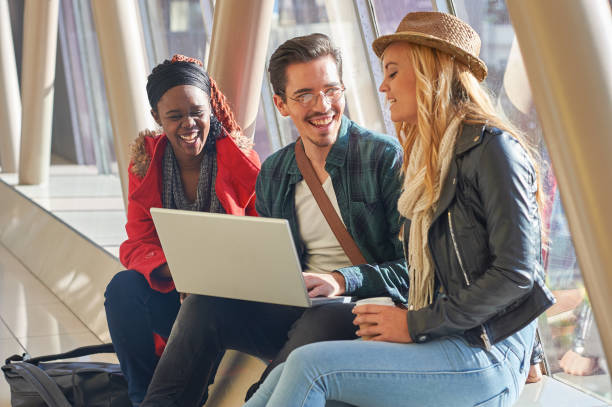 3 young adults entrepreneurs or students group mixed race around laptop having a discussion stock photo