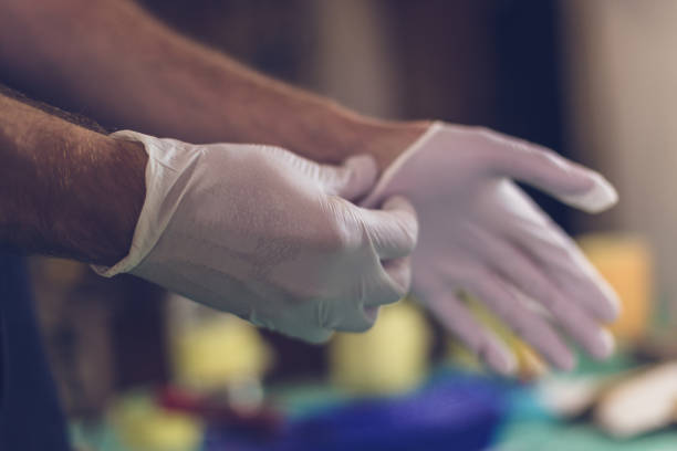 hombre manos poner en guantes de látex - guante quirúrgico fotografías e imágenes de stock