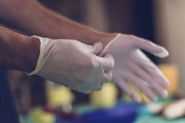 Male hands putting on latex gloves Close-up of man hands putting protective latex gloves on in the workshop. glove stock pictures, royalty-free photos & images