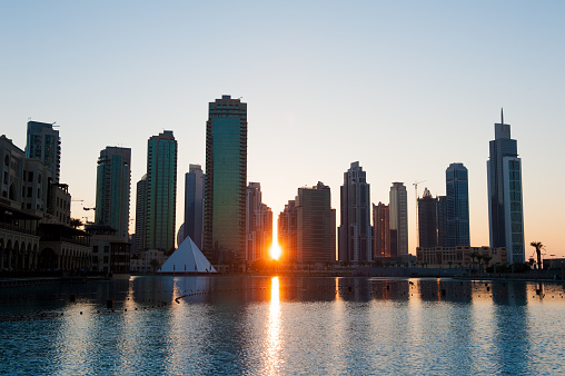Sun is setting between the modern skyscrapers in Dubai, UAE