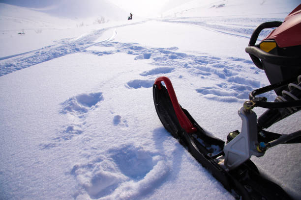 Ski of snowmobile and remote snowmobile silhouette in snowfield. Mountain pass and blizzard in   Khibiny Mountains,  Kola Peninsula, Russia -  Symbol  North and severe Ski of snowmobile and remote snowmobile silhouette in snowfield. Mountain pass and blizzard in   Khibiny Mountains,  Kola Peninsula, Russia -  Symbol  North and severe Snowmobiling stock pictures, royalty-free photos & images