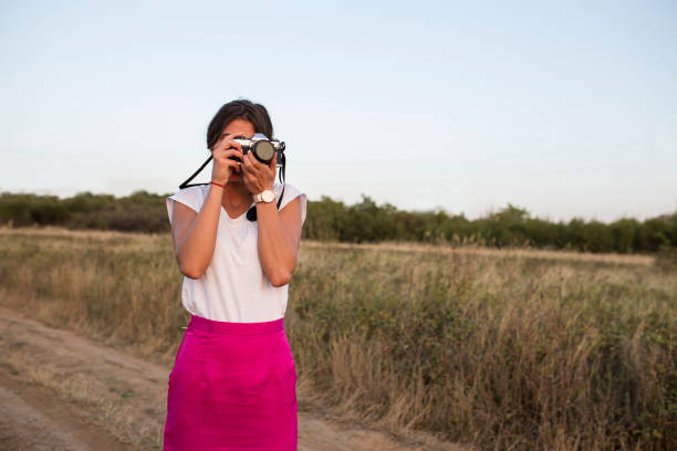 Young woman with vintage camera in nature taking pictures