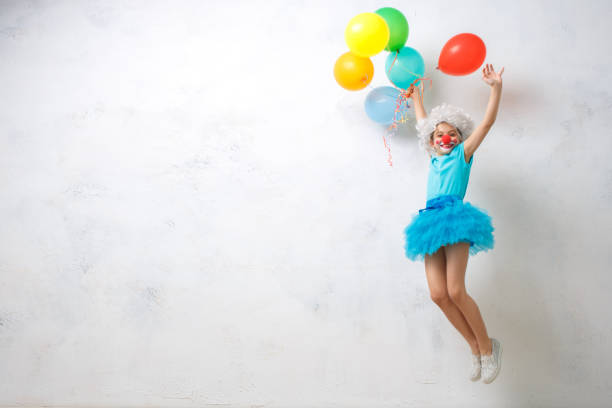 kleine mädchen tragen clown kostüm isoliert auf weiss - child balloon happiness cheerful stock-fotos und bilder