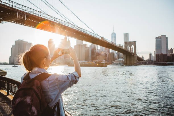 That's a view you just have to capture! Woman photographing New York skyline at dusk brooklyn bridge photos stock pictures, royalty-free photos & images