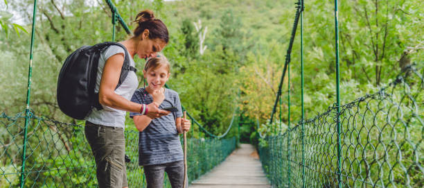 istock Mother and daughter using smart phone on the wooden bridge 841523208