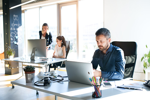 Three business people in the workplace. Two women and man sitting in the office working together.