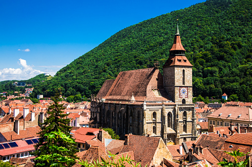 High angle view of the ancient medieval town of Brasov, in the Transylvania region of Romania. The old houses have orange tiled roofs, and what is known as the 'Black Church' dominates the center of the town. Colour image with copy space.