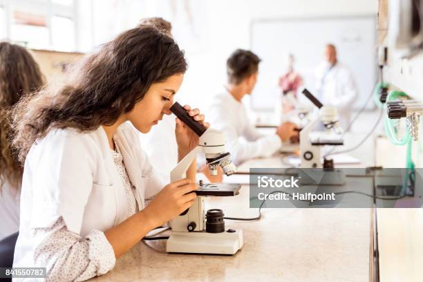 Foto de Estudante Do Colegial Linda Com Microscópio No Laboratório e mais fotos de stock de Ciência