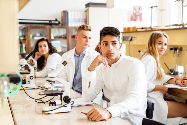 High school student with microscopes in laboratory. Group of high school student with microscopes in laboratory during biology class. high school high school student science multi ethnic group stock pictures, royalty-free photos & images