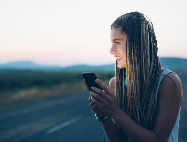 istock Smiling young woman using smart phone on country road 841562144