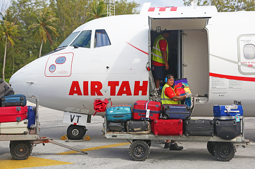 A worker unloads bagages from the aircraft just landed at Bora Bora airport