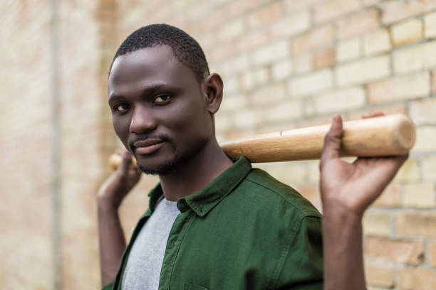 istock handsome african-american man with baseball bat on shoulders 841573726