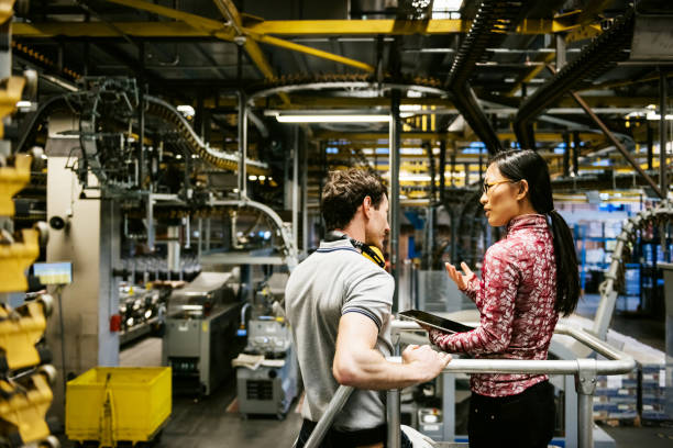 mecánico e ingeniero mujer hablando en fábrica - chinese production fotografías e imágenes de stock