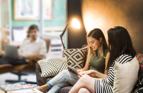 クリエイティブ ・ オフィスのソファーに座りながらデジタル タブレットを見て若い実業家 - digital tablet businesswoman young women watching ストックフォトと画像