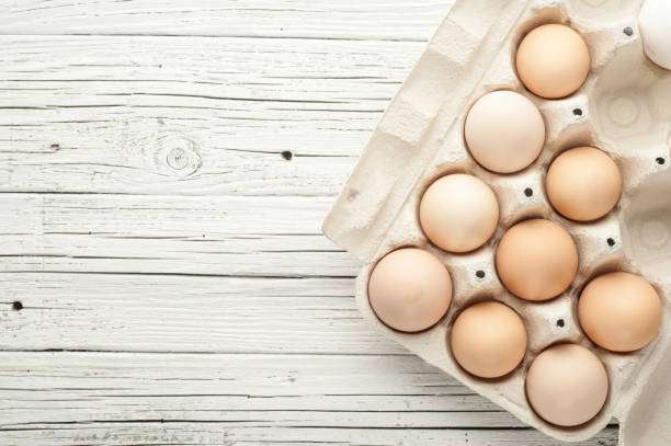 istock chicken eggs in cardboard box on white wooden background 841577646