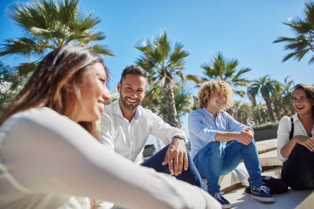 istock Happy young people sitting together outside laughing 841584588