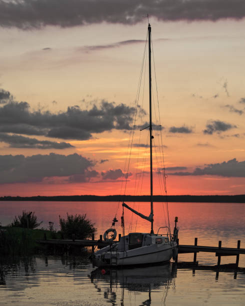 coucher de soleil coloré au lac avec la silhouette du voilier à quai dans le port - steinhuder meer photos et images de collection