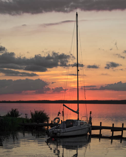 tramonto colorato al lago con silhouette di barca a vela al molo nel porto - steinhuder meer foto e immagini stock