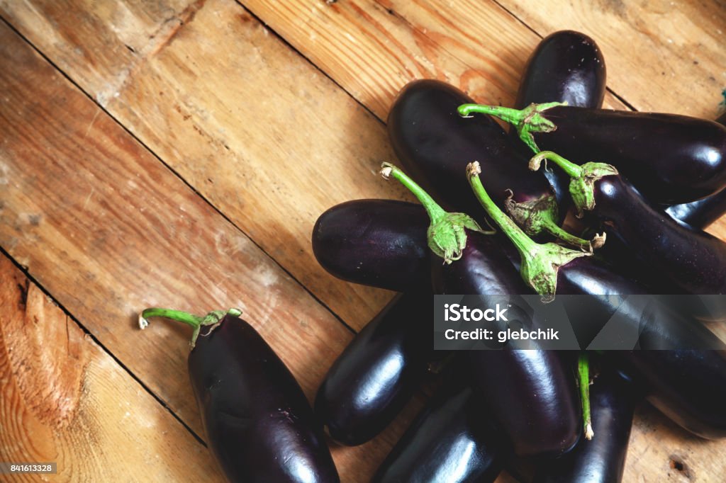 Several ripe eggplant lay on boards group of blue ripe eggplants with green tails lie on old wooden boards planed"n Agriculture Stock Photo