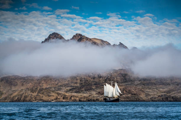 Low lying clouds over schooner under full sail in Greenland