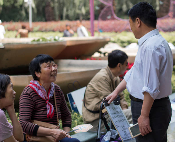 genitori speranzosi di uomini e donne rimasti frequentano il mercato del matrimonio al people's park per fare un fiammifero per i loro figli single. gli annunci senza foto per i non sposati sono scritti su carta sugli ombrelli - peoples park foto e immagini stock