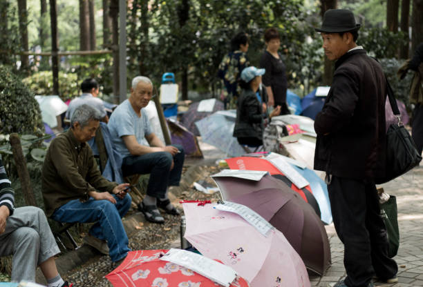 genitori speranzosi di uomini e donne rimasti frequentano il mercato del matrimonio al people's park per fare un fiammifero per i loro figli single. gli annunci senza foto per i non sposati sono scritti su carta sugli ombrelli - peoples park foto e immagini stock