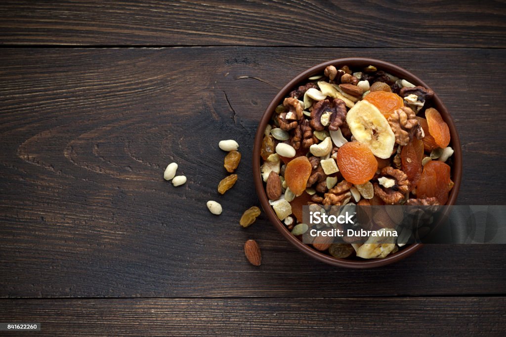 Healthy snacks in bowl on wooden background. Healthy snacks in bowl on wooden background. Dried fruits and nuts. Top view, copy space. Nut - Food Stock Photo