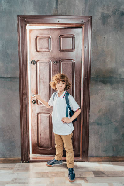 istock cute little boy going to school, standing next to door 841629016