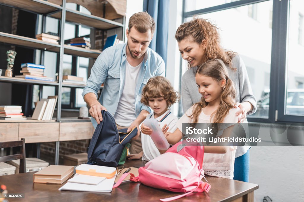 genitori imballaggio bambini per il loro primo giorno a scuola - Foto stock royalty-free di Riapertura delle scuole