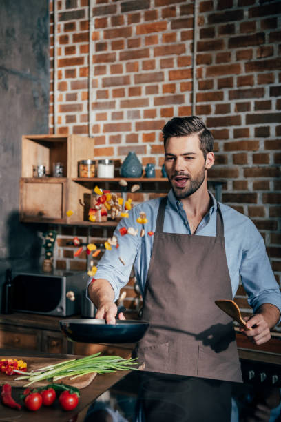 istock handsome excited man with apron frying vegetables 841643202