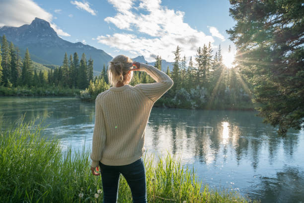 istock Blond girl watching sunrise from river bank 841647104