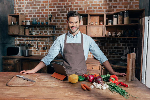 istock handsome young man in apron on kitchen with fresh vegetables on table 841647720