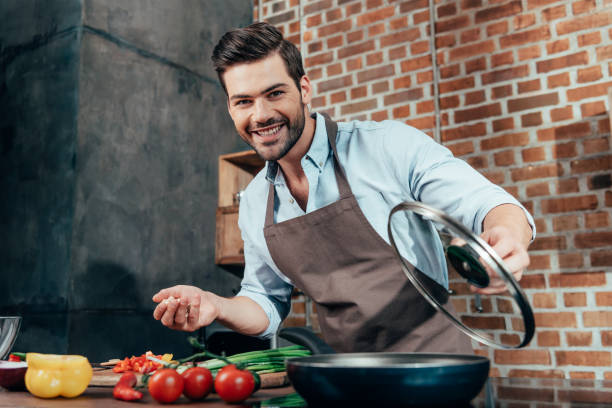 istock smiling handsome young man with apron cooking 841659596