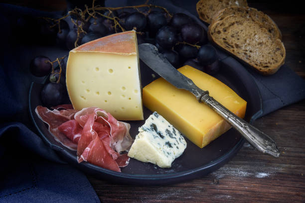 istock supper plate with various cheese, air dried ham, blue grapes and bread on dark rustic wood, selected focus 841660008