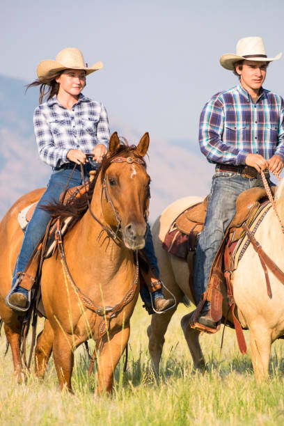 istock Young couple Horse back riding through long grassy area on a ranch 841663372