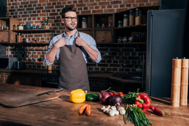istock stylish young man in apron on kitchen with fresh vegetables on table 841663814