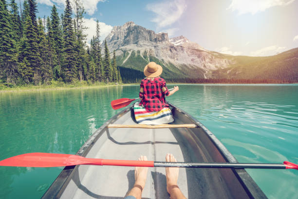 Pov of couple paddling red canoe on turquoise lake View of a young couple canoeing on beautiful mountain lake in Canada yoho national park photos stock pictures, royalty-free photos & images