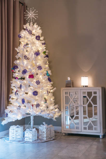 istock White Christmas tree with white wrapped presents beside a white cabinet 841676328