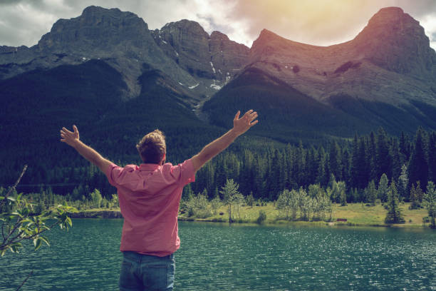 istock Young man arms outstretched at mountain lake 841676672