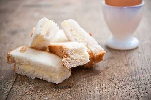 closeup of Soft boiled egg in egg cup and served with toast fingers on wooden table