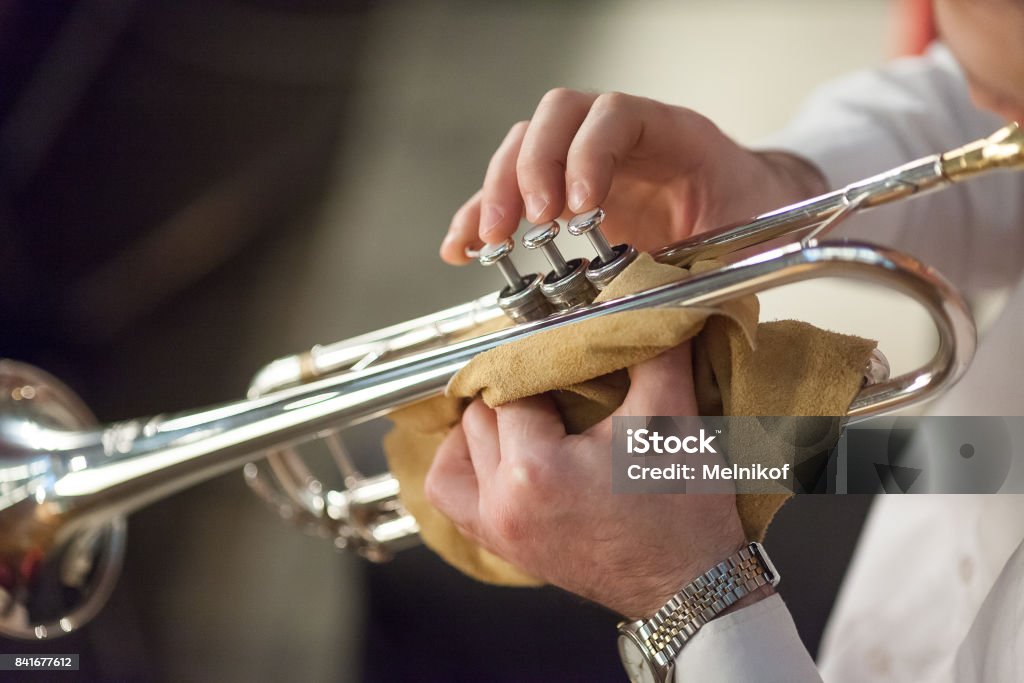 music, jazz, art concept. there is the most popular jazz instrument, trumpet, in old groomed hands of male professional player, he has simple but shiny silver wristwatch on the left hand Orchestra Pit Stock Photo