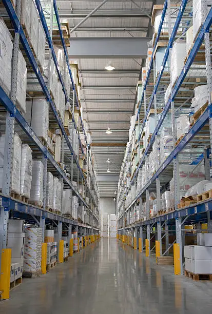 Tall warehouse shelving aisle in paper factory.  Indoors.