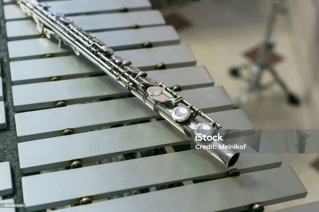 symphonic and brass band, percussion and wind instruments concept - beautiful closeup on shiny western concert flute lies on xylophone, education and orchestra concert, beige bars without mallets Arts Culture and Entertainment Stock Photo